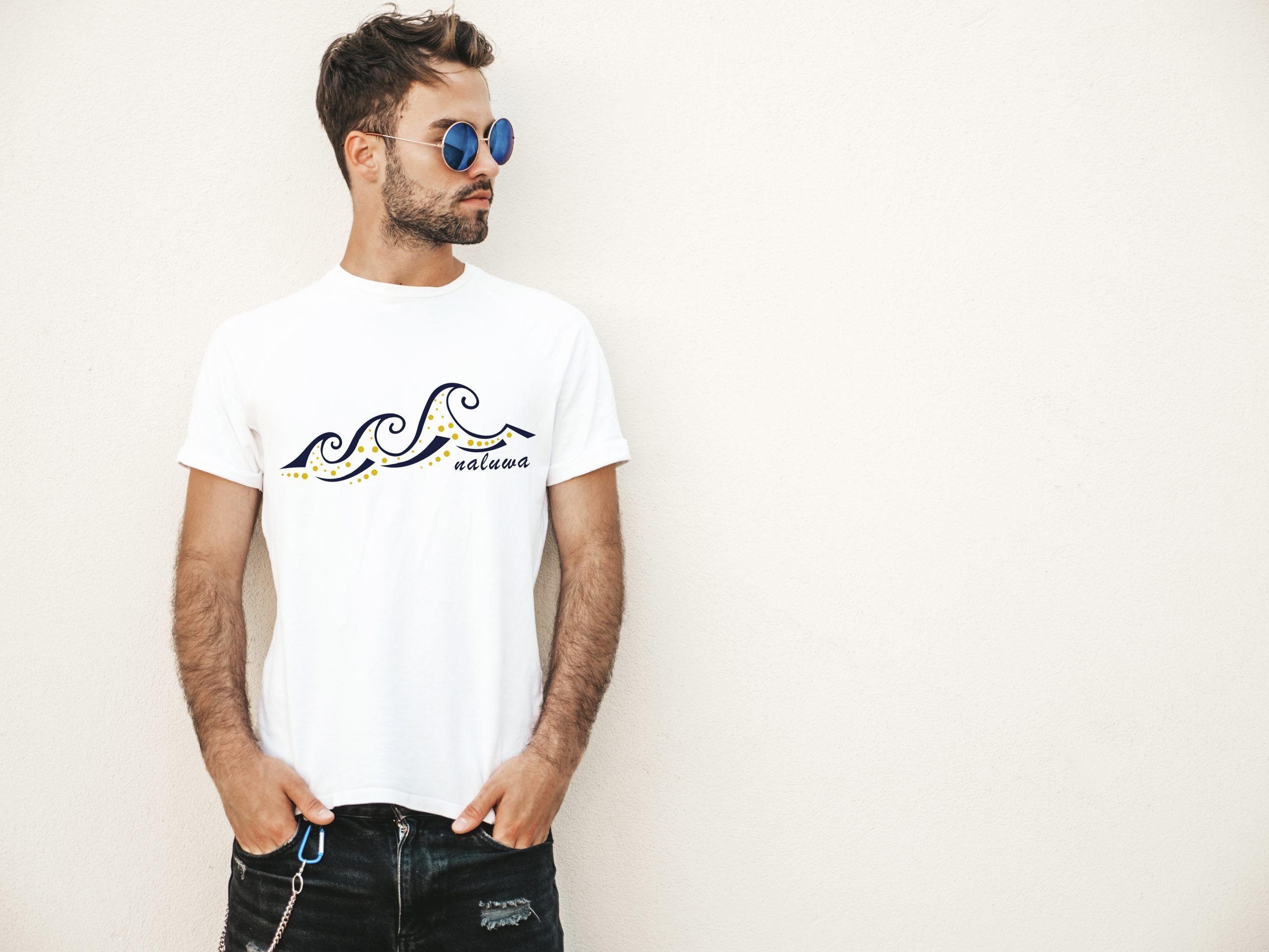 Portrait of handsome confident stylish hipster lambersexual model.Man dressed in white T-shirt. Fashion male posing on the street background near wall in sunglasses outdoors